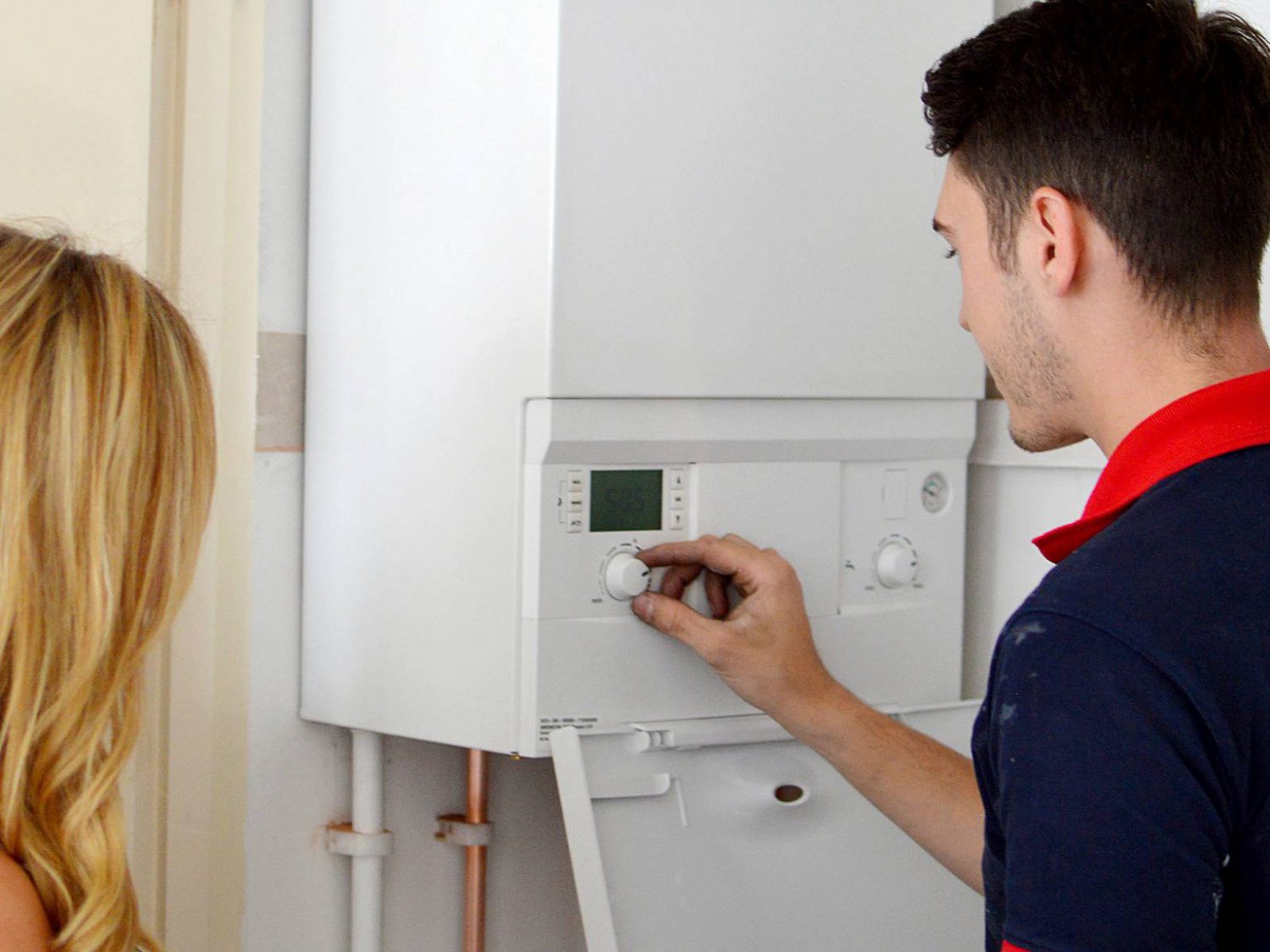 A woman looking on as a plumber fixes her boiler