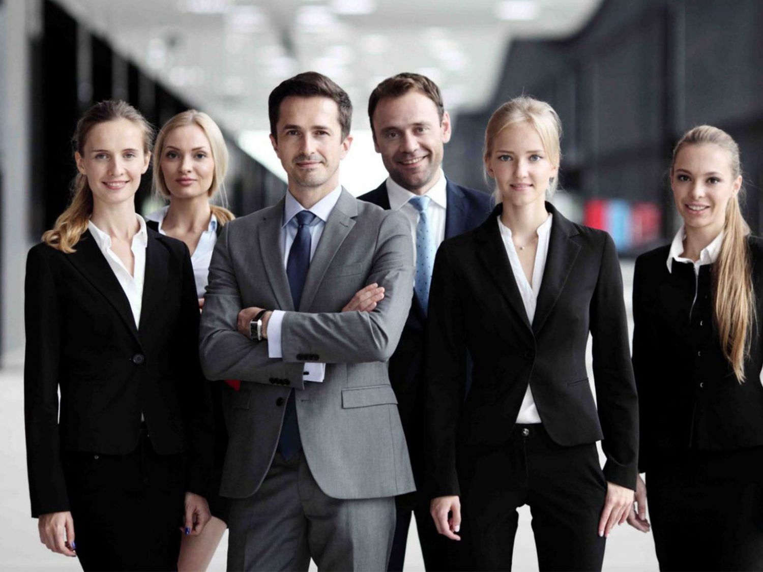 Six corporate employees standing together facing the camera