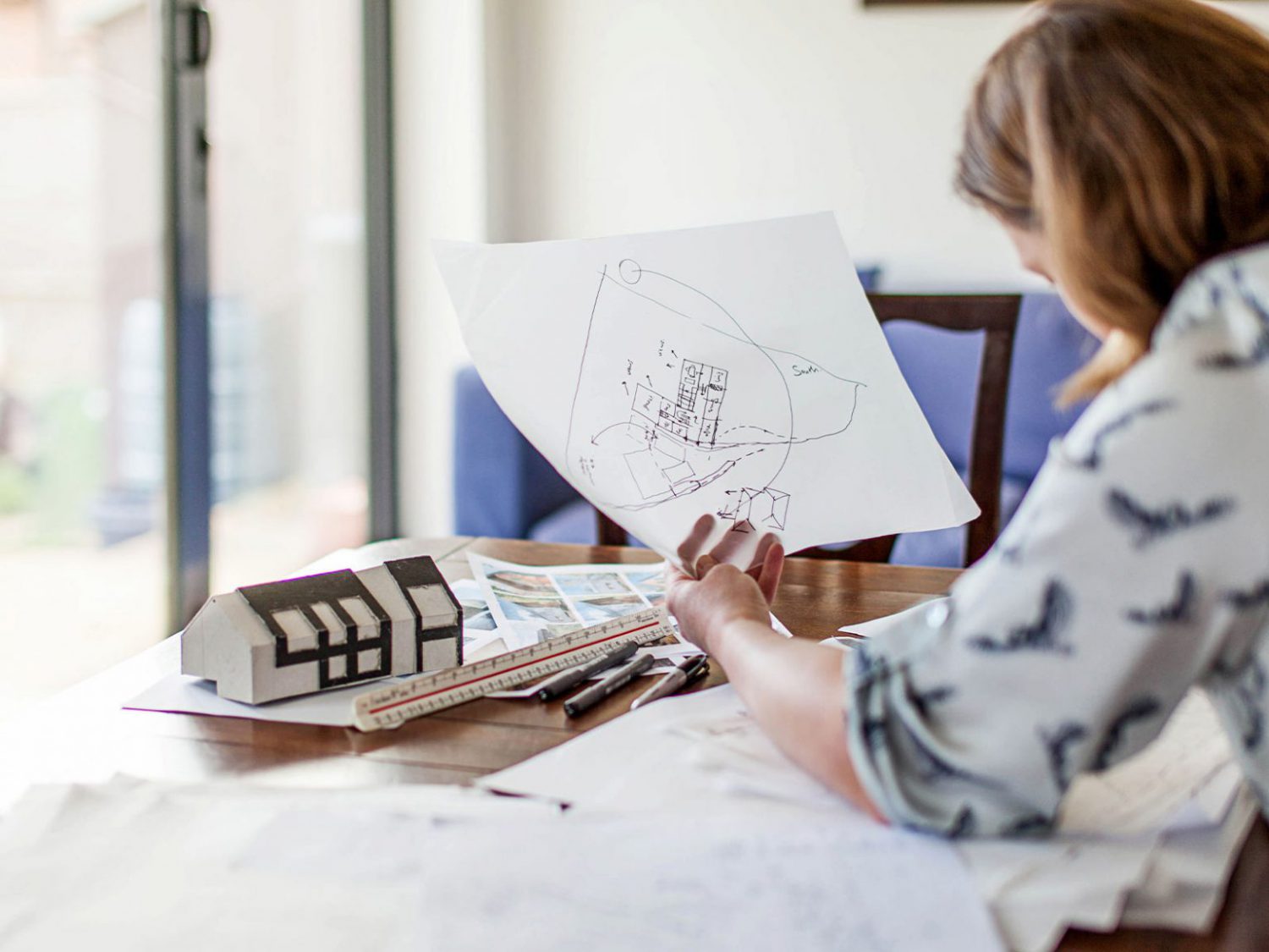 An architect tracing some sketches while holding one in her left hand